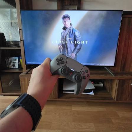 Jogador com comando PlayStation 5 diante da televisão